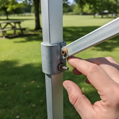 Hand inspecting a pop-up gazebo frame for wear and tear, close-up, outdoors